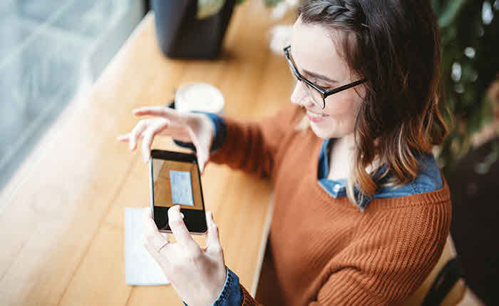 woman taking picture of check with phone