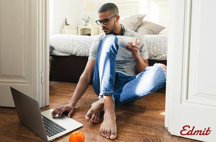 student sitting on floor and looking at laptop